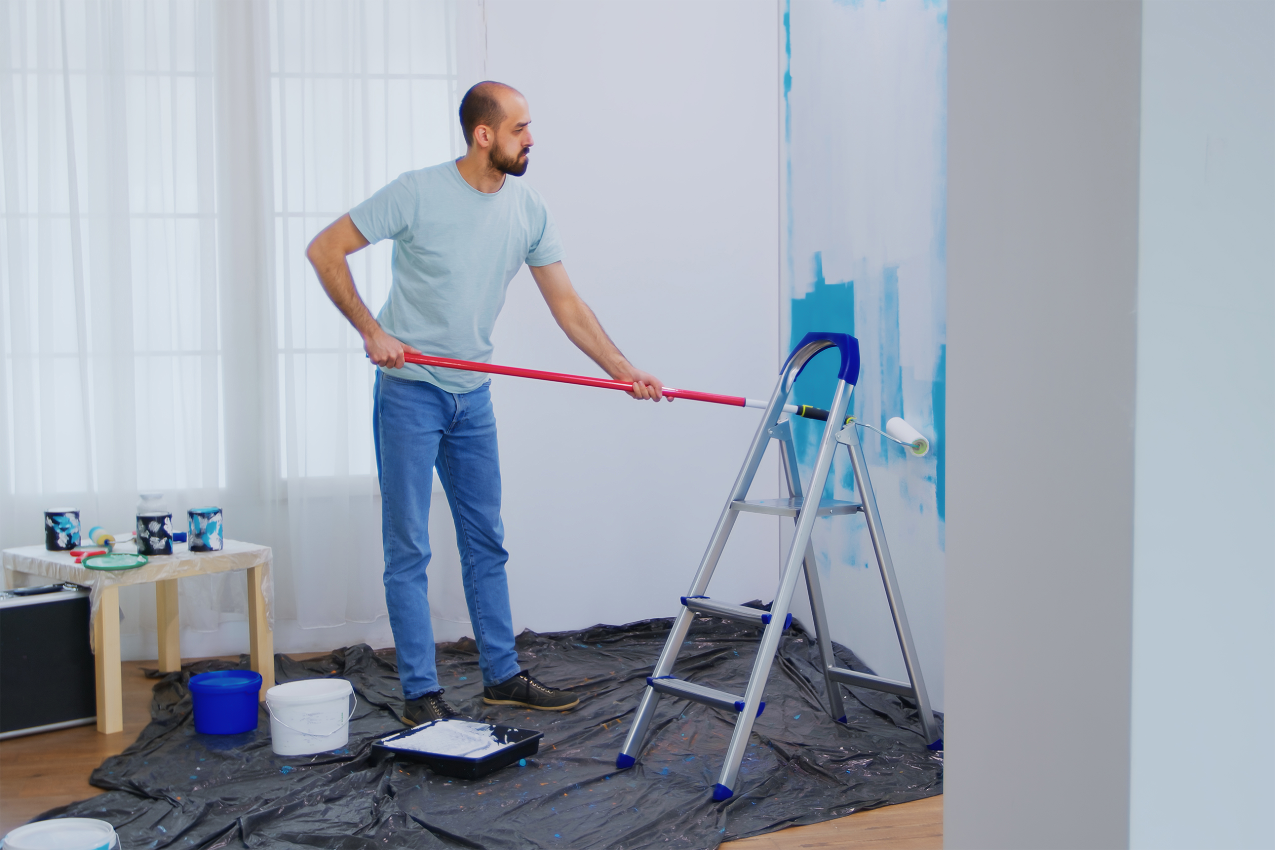 masaking-blue-paint-with-roller-brush-dipped-white-paint-handyman-renovating-apartment-redecoration-home-construction-while-renovating-improving-repair-decorating3